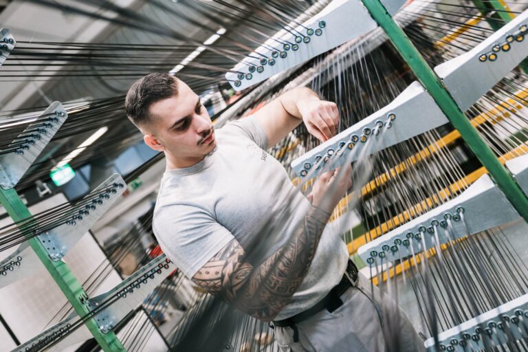 Mann mit Tätowierungen arbeitet in einer Fabrik